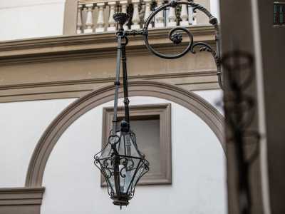 Dai muri pendono stupendi lampadari in ferro battuto decorato con foglie e fiori...